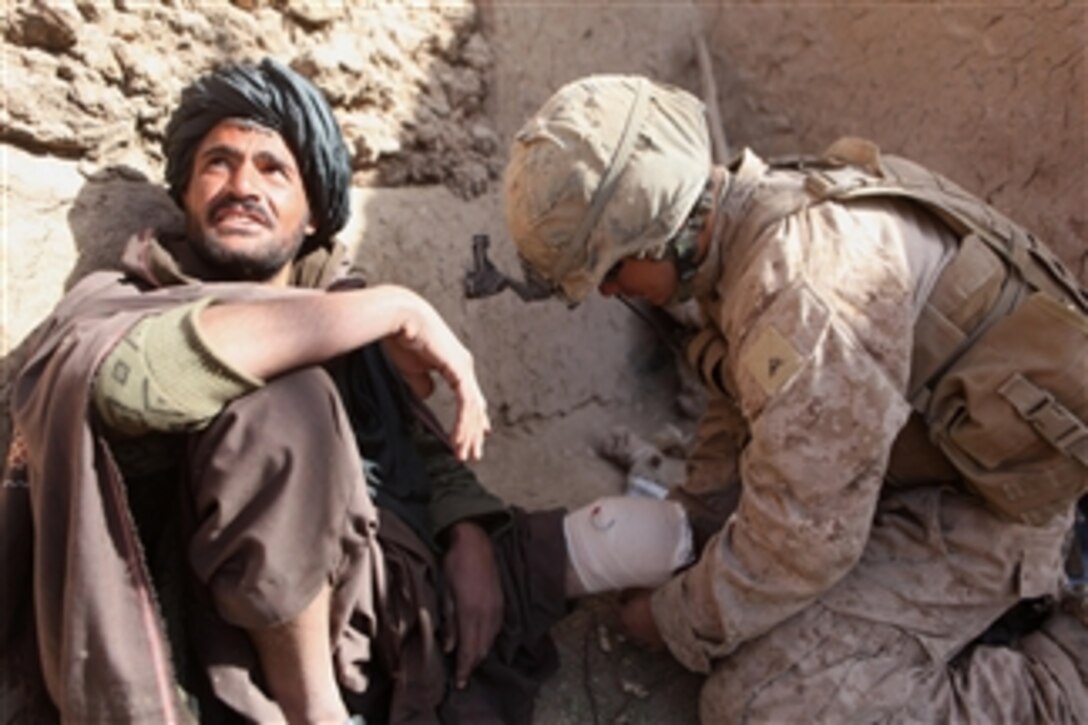 U.S. Marine Corps Lance Cpl. Josh N. Rees (right), a team leader with 2nd Squad, 2nd Platoon, Fox Company, 2nd Battalion, 9th Marine Regiment, Regimental Combat Team 1, wraps an Afghan man's knee during a security patrol in Marjah, Afghanistan, on Jan. 3, 2011.  The man hurt his knee while working in his field.  The Marines conducted security patrols in Helmand province in support of the International Security Assistance Force.  