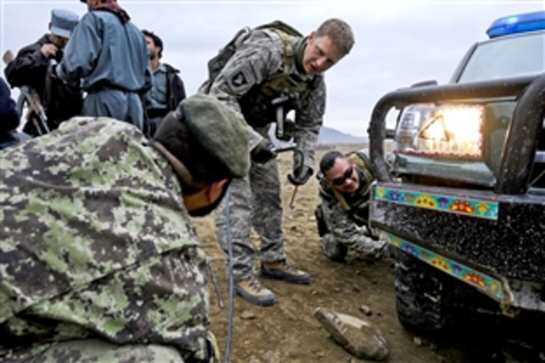 U.S. Army Sgt. 1st Class Manuel Delarosa, right, and Staff Sgt. Joshua Harkema inflate an Afghan police truck tire in Safidar village, Afghanistan, Feb. 1, 2011. Delarosa and Harkema, assigned to Provincial Reconstruction Team Zabul, and Afghan security forces distributed winter supplies and talked with village elders.