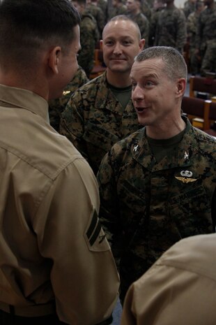 Col. James C. Stewart, station commanding officer, greets and congratulates Cpl. Michael A. Clemens, Corporals Course honor graduate, after the Coporals Course Class 4-11 graduation ceremony at the Marine Memorial Chapel here Feb. 3.