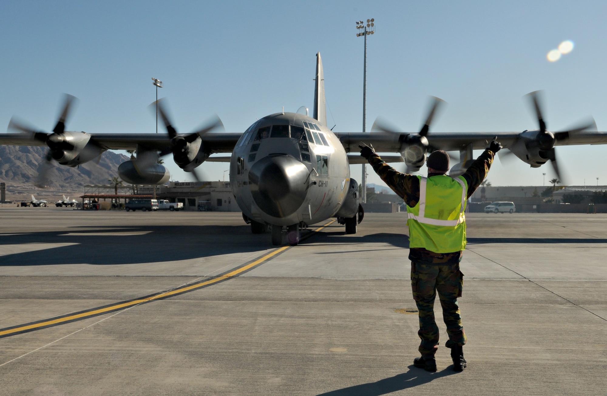 NELLIS AIR FORCE BASE, Nev. -- 1st Cpl. Lesoil Poscol, aircraft maintainer, marshals a C-130 Hercules from the Belgium air force's 20 Squadron Feb. 2 after completing a mission in Red Flag 11-2. The C-130 and Corporal Poscol are deployed from Melsbroek Air Base, Belgium, to participate in the combined exercise that provides a realistic combat training environment to the U.S. and its allies. (U.S. Air Force photo/Staff Sgt. Benjamin Wilson)