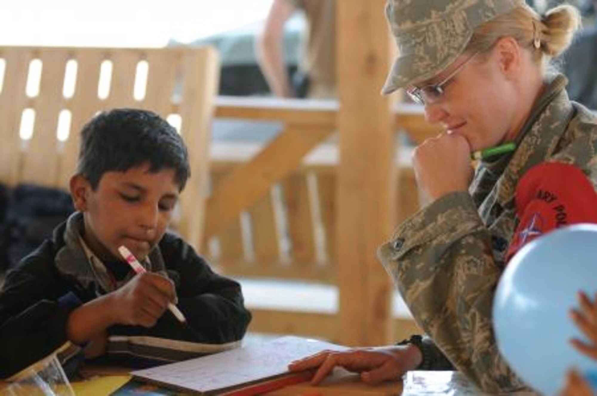 AFGHANISTAN -- Senior Airman Christena Alotaibi plays tic-tac-toe with an Afghan boy while volunteering at a school for boys ages 6 to 16. Airman Alotaibi volunteered at the school while deployed to the region. Along with her community service, she was named the 434th Air Refueling Wing's Airman of the Year for 2010 for her significant self-improvement and outstanding job performance. (Courtesy photo) 