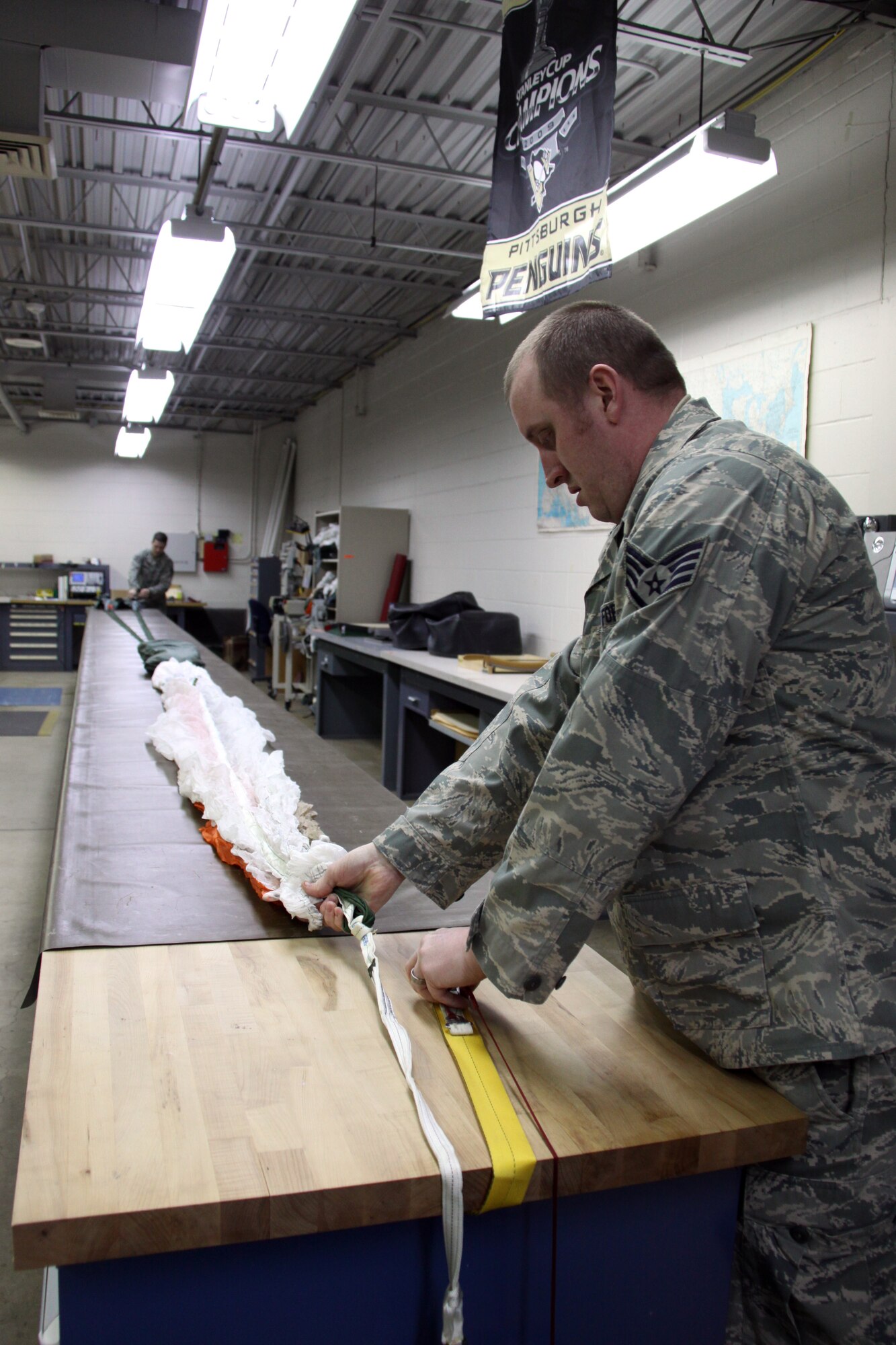Staff Sgts. Jason Cornelius, noncommissioned officer in charge of training, aircrew flight equipment, 911th Operations Support Squadron and Matt Walsh, an aircrew flight equipment specialist with the 911th OSS stretches out a BA-18 back parachute for inspection here, Feb. 2. Regular inspections are needed in order to keep life support equipment for C-130H aircraft aircrews functional and ready for emergencies. 