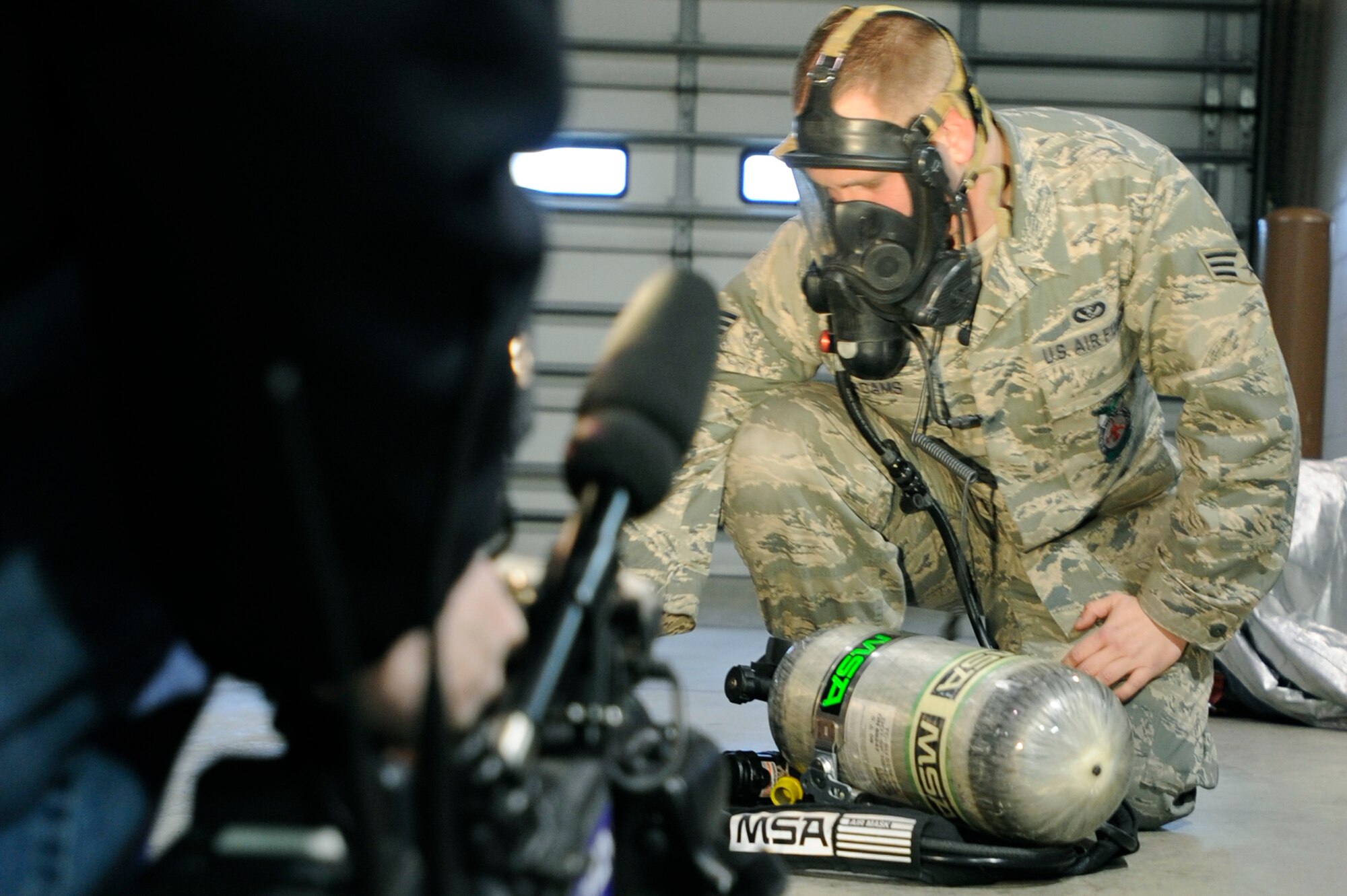 Senior Airman Jared Adams demonstrates a self-contained breathing apparatus to reporters from KWCH-TV, a Wichita, Kan., television station Jan. 31, 2011, at McConnell Air Force Base, Kan. Airman Adams is a firefighter assigned to the 22nd Civil Engineer Squadron. He was recognized by KWCH-TV reporters for rescuing a couple from a house fire. (U.S. Air Force photo/Airman 1st Class Armando A. Schwier-Morales)