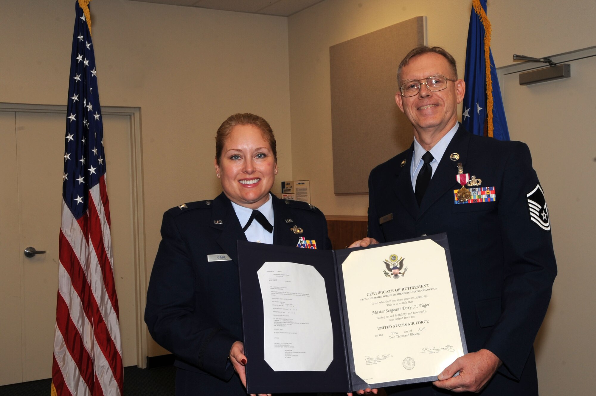 Director of Pacific Air Forces Public Affairs, Colonel Maria Carl, presents the certificate of retirement to MSgt Daryl Yager.