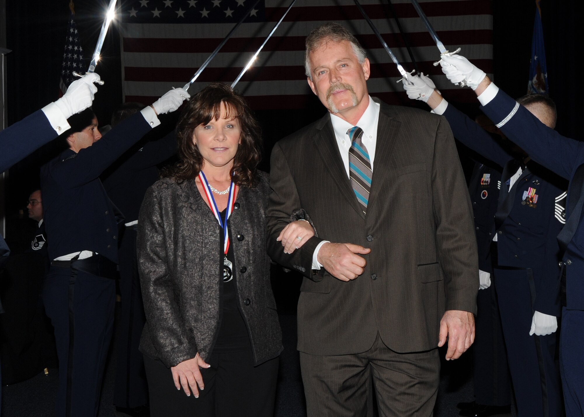 Vickie Hayden, 22nd Air Refueling Wing Sexual Assault Response coordinator, and husband Lance Hayden, walk through the sabers as part of the annual awards ceremony held in the Robert J. Dole Community Center ballroom, Jan. 28, 2011, McConnell Air Force Base, Kan. Mrs Hayden won the 2010 Civilian Category I of the Year. (U.S. Air Force photo/Airman 1st Class Katrina M. Brisbin)