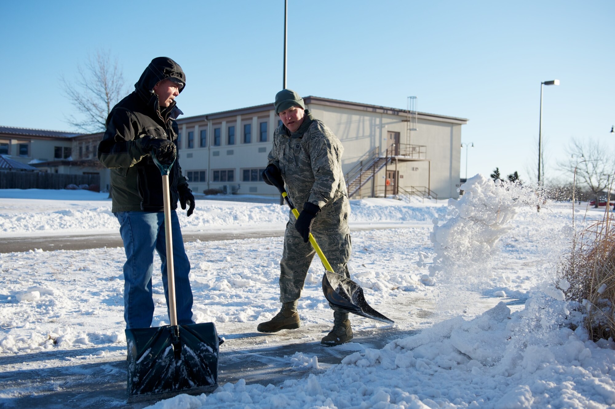 Master Sgt. Leonard Green and Charles Hale, 22nd Force Support Squadron Manpower analysts, shovel snow Feb. 2, 2011, McConnell Air Force Base, Kan.  The snow was the result of a massive winter storm that stretched across more than 2,000 miles from Texas to New England.  (U.S. Air Force photo/Staff Sgt. Michael Shocker)
