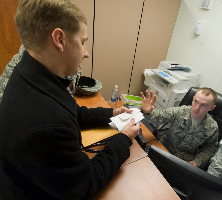 Captain Eric Heinzer, Headquarters Element staff officer, hands car rental receipts to Airman 1st Class John Theison, 11th Comptroller Squadron, customer service technician, as part of travel pay reimbursement. (U.S. Air Force photo/Bobby Jones)