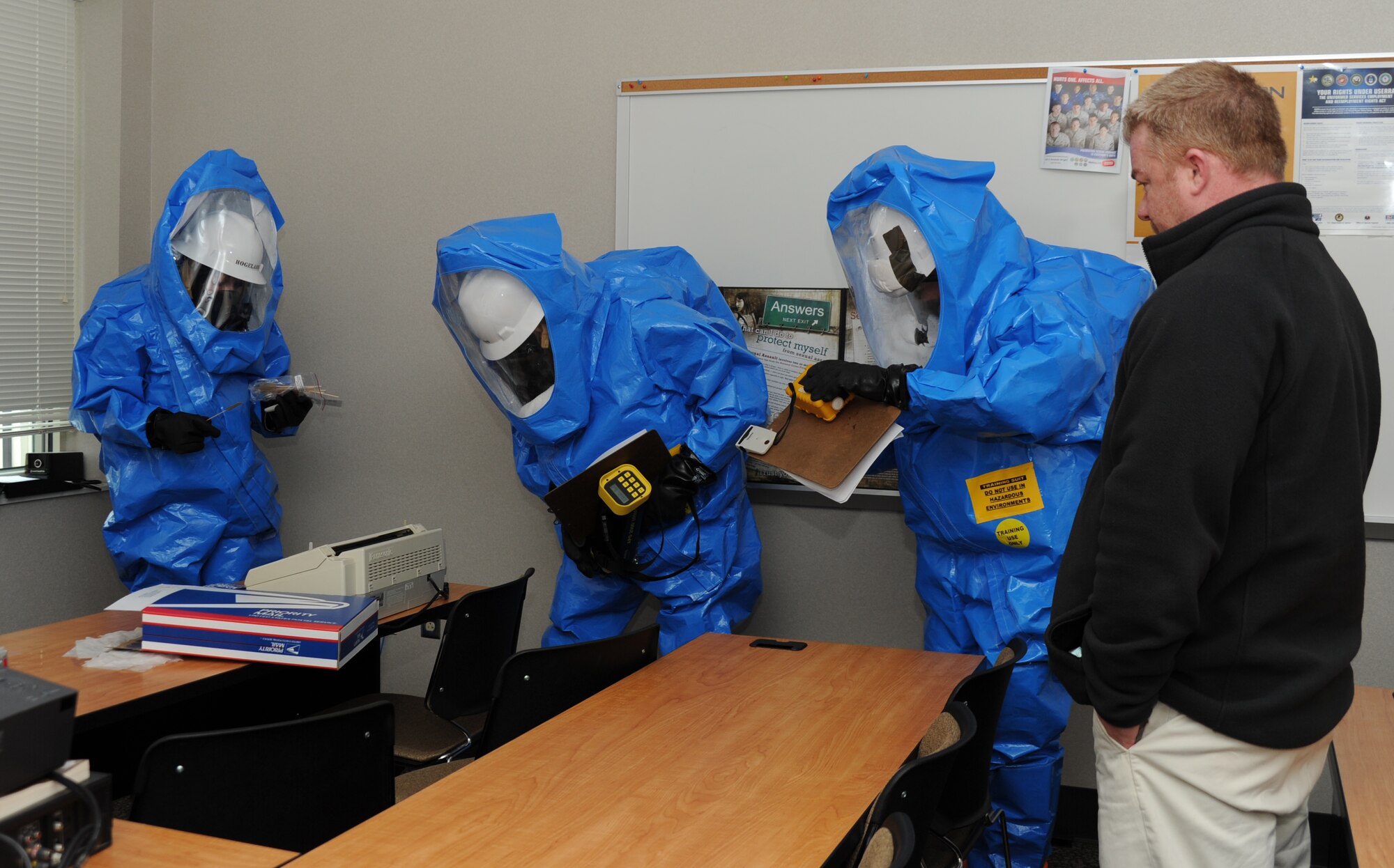 From left: Staff Sgt. Chris Clark, 241st Engineering Installation Squadron, 118th AW, Senior Airman Tiffany Hogeland, 118th Civil Engineering, and Staff Sgt. Joshua Dow, 118th Bioenvironmental Engineering, assess the room and take readings of the air quality before taking a sample of an "unknown" substance on the table that was simulated to have come from the mail package Jan. 26 during the National Guard Bureau's all hazard response training that took place at the base Jan. 24-28. Far right: a member of L3, which was contracted by NGB, watches the team in action and helps them learn to use the equipment.