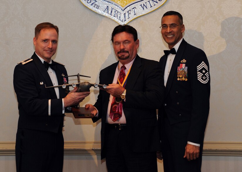 Col. John Wood, left, and Chief Master Sgt. Terrence Greene, right, presents Mr. John Hoffman the Civilian Category II of the Year award for 2010 during the annual awards banquet held at the Charleston Club Feb 2. Airmen and civilians were presented an award for their outstanding accomplishments from one of the 15 different different categories recognized. Unable to attend the banquet due to deployment or other reasons were, from the 437th Operations Support Squadron, Airmen of the Year Senior Airman John Konkol; from the 16th Airlift Squadron, Senior Noncommissioned Officer of the Year Master Sgt. Jefferey Faretra; from the 437th Aircraft Maintenance Squadron, Second Leiutenant Travis Mongeon; and from the 16th Airlift Squadron, Civilian Category 1 of the Year Mr. Timothy Peyton. Colonel Wood is the 437th Airlift Wing commander, Chief Greene is the 437th Airlift Wing command chief and Mr. Hoffman is from the 437th Operations Support Squadron. (U.S. Air Force photo/Senior Airman Timothy Taylor)