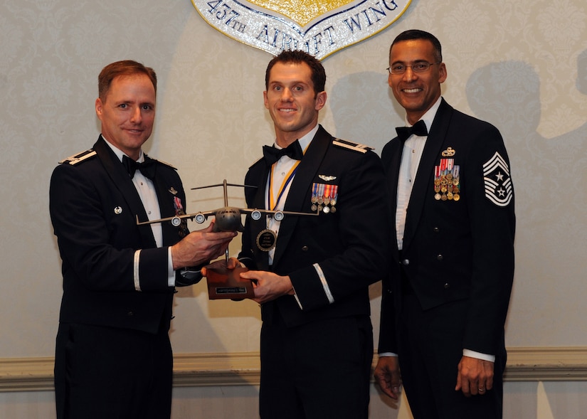 Col. John Wood, left, and Chief Master Sgt. Terrence Greene, right, presents Capt. Christopher Pace the Senior Company Grade Officer of the Year award for 2010 during the annual awards banquet held at the Charleston Club Feb 2. Airmen and civilians were presented an award for their outstanding accomplishments from one of the 15 different different categories recognized. Unable to attend the banquet due to deployment or other reasons were, from the 437th Operations Support Squadron, Airmen of the Year Senior Airman John Konkol; from the 16th Airlift Squadron, Senior Noncommissioned Officer of the Year Master Sgt. Jefferey Faretra; from the 437th Aircraft Maintenance Squadron, Second Leiutenant Travis Mongeon; and from the 16th Airlift Squadron, Civilian Category 1 of the Year Mr. Timothy Peyton. Colonel Wood is the 437th Airlift Wing commander, Chief Greene is the 437th Airlift Wing command chief and Captain Pace is from the 437th Operations Support Squadron. (U.S. Air Force photo/Senior Airman Timothy Taylor)