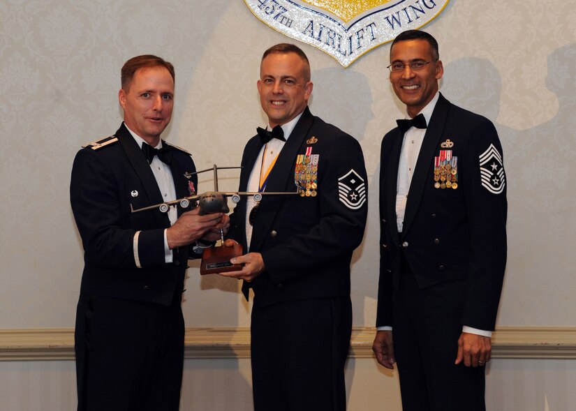 Col. John Wood, left, and Chief Master Sgt. Terrence Greene, right, presents Master Sgt. Jeffrey Tynan the First Sergeant of the Year award for 2010 during the annual awards banquet held at the Charleston Club Feb 2. Airmen and civilians were presented an award for their outstanding accomplishments from one of the 15 different different categories recognized. Unable to attend the banquet due to deployment or other reasons were, from the 437th Operations Support Squadron, Airmen of the Year Senior Airman John Konkol; from the 16th Airlift Squadron, Senior Noncommissioned Officer of the Year Master Sgt. Jefferey Faretra; from the 437th Aircraft Maintenance Squadron, Second Leiutenant Travis Mongeon; and from the 16th Airlift Squadron, Civilian Category 1 of the Year Mr. Timothy Peyton. Colonel Wood is the 437th Airlift Wing commander, Chief Greene is the 437th Airlift Wing command chief and Sergeant Tynan is from the 437th Operations Support Squadron. (U.S. Air Force photo/Senior Airman Timothy Taylor)