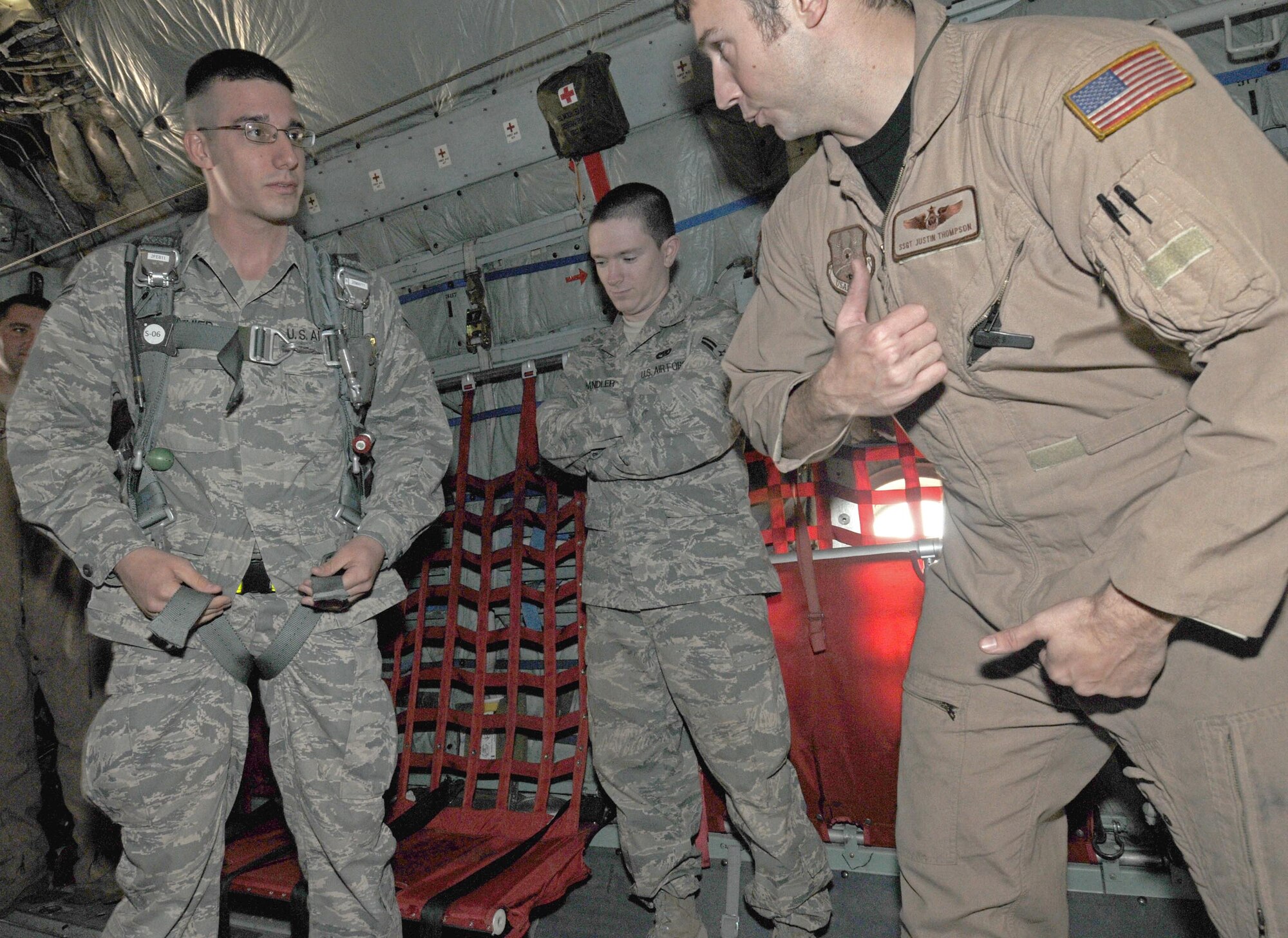 Senior Airman Christopher Gauthier, a cyber transport technician with the 386th Expeditionary Communications Squadron, adjusts the straps of a parachute while Staff Sgt. Justin Thompson, a loadmaster with the 737th Expeditionary Airlift Squadron, shows him the easiest way during the Quarry Open House here, Feb. 2. Airmen who don't usually work on the flightline, or Quarry, were given a chance to see what goes on during the open house. (U.S. Air Force photo by Staff Sgt. Patrice Clarke)