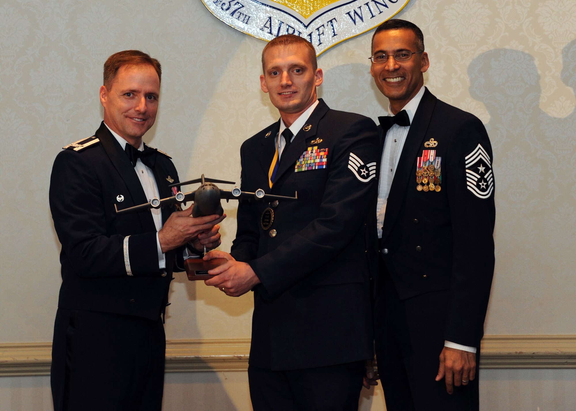 Col. John Wood, left, and Chief Master Sgt. Terrence Greene (right), present Staff Sgt. Robert Pennington the Noncommissioned Officer of the Year award for 2010 during the annual 437th Air Lift Wing awards banquet, held at the Charleston Club Feb. 2, 2011. Colonel Wood is the 437 AW commander, Chief Greene is the 437 AW command chief and Sergeant Pennington is from the 437th Maintenance Group. (U.S. Air Force photo/Senior Airman Timoty Taylor)
