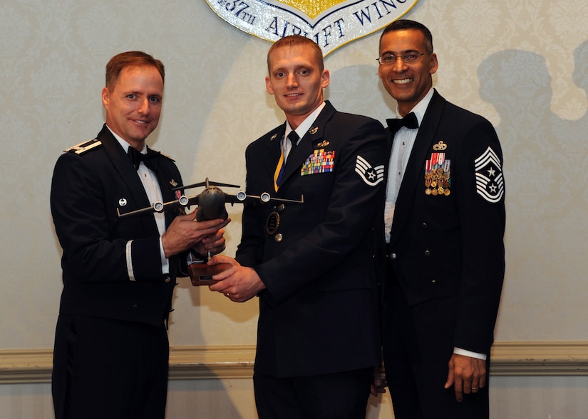 Col. John Wood, left, and Chief Master Sgt. Terrence Greene (right), present Staff Sgt. Robert Pennington the Noncommissioned Officer of the Year award for 2010 during the annual 437th Air Lift Wing awards banquet, held at the Charleston Club Feb. 2, 2011. Colonel Wood is the 437 AW commander, Chief Greene is the 437 AW command chief and Sergeant Pennington is from the 437th Maintenance Group. (U.S. Air Force photo/Senior Airman Timoty Taylor)