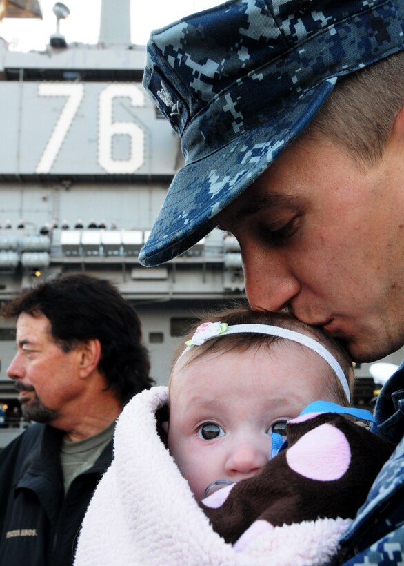 U.S. Navy Petty Officer 3rd Class Daniel Rawson kisses his daughter Giana Lee Rawson before saying goodbye to his family while on the pier in front of the aircraft carrier USS Ronald Reagan, Feb. 2, 2011.