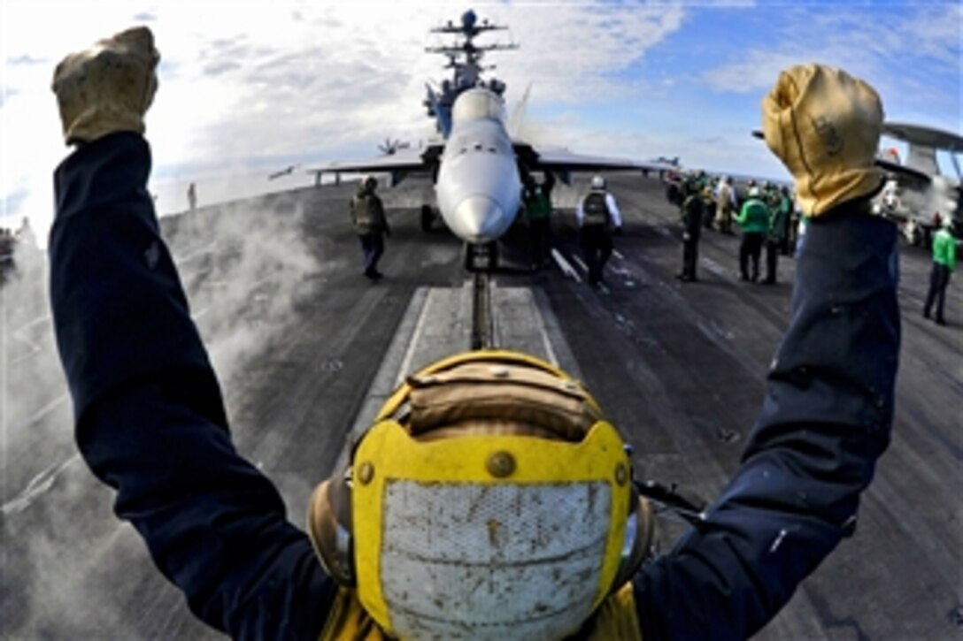 An aircraft director guides an F/A-18C Hornet onto a catapult aboard the aircraft carrier USS Harry S. Truman (CVN 75) in the Atlantic Ocean on Feb. 1, 2011.  The Harry S. Truman is supporting fleet replacement squadron carrier qualifications.  