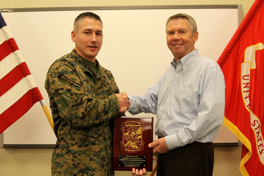 Capt. Jaymes Roedl (left), officer-in-charge, Train the Trainer School, School of Infantry West, congratulates Robert E. Gillespie, senior consultant, Information Reliance Corporation, SOI-West, for his continuous and faithful service since 1987. The school is recognizing Gillespie’s hard work and dedication by naming the largest classroom in building 520523, after him and hanging a plaque on the wall in his honor, Feb. 3. For more than two decades, Gillespie has provided customer support for the Marine Corps Training Information Management Systems for all Marine Corps units west of the Mississippi.