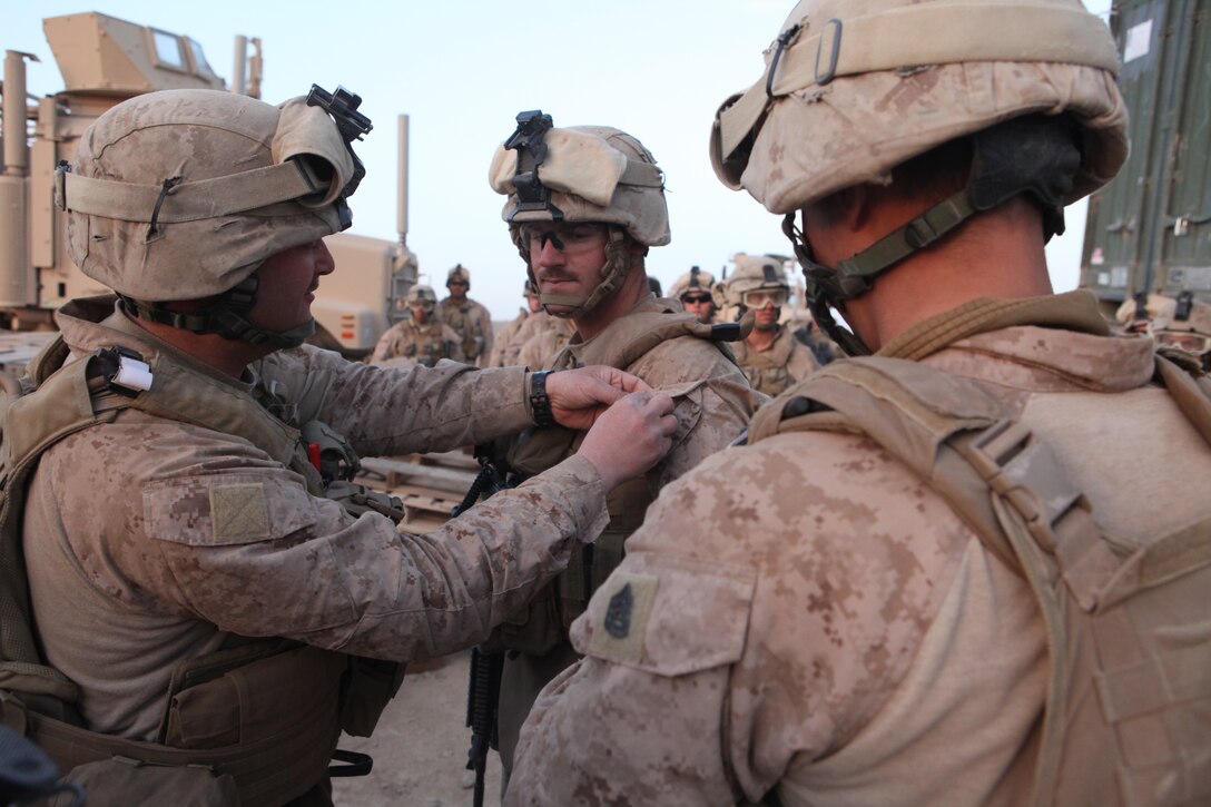 U.S. Marine Corps Gunnery Sgt. Justin A. Smith (left), and U.S. Marine Corps Gunnery Sgt. Jonathan E. Novak, both vehicle commanders with Quick Response Force, pin U.S. Marine Corps Gunnery Sgt. rank on Anthony A. Joens, a vehicle commander with Quick Response Force, Company L, Battalion Landing Team 3/8, 26th Marine Expeditionary Unit, Regimental Combat Team 2, during a promotion ceremony held near Combat Outpost Ouellette in the Helmand province, Afghanistan, Feb. 4, 2011. Elements of the 26th Marine Expeditionary Unit deployed to Afghanistan to provide regional security in Helmand province in support of the International Security Assistance Force.