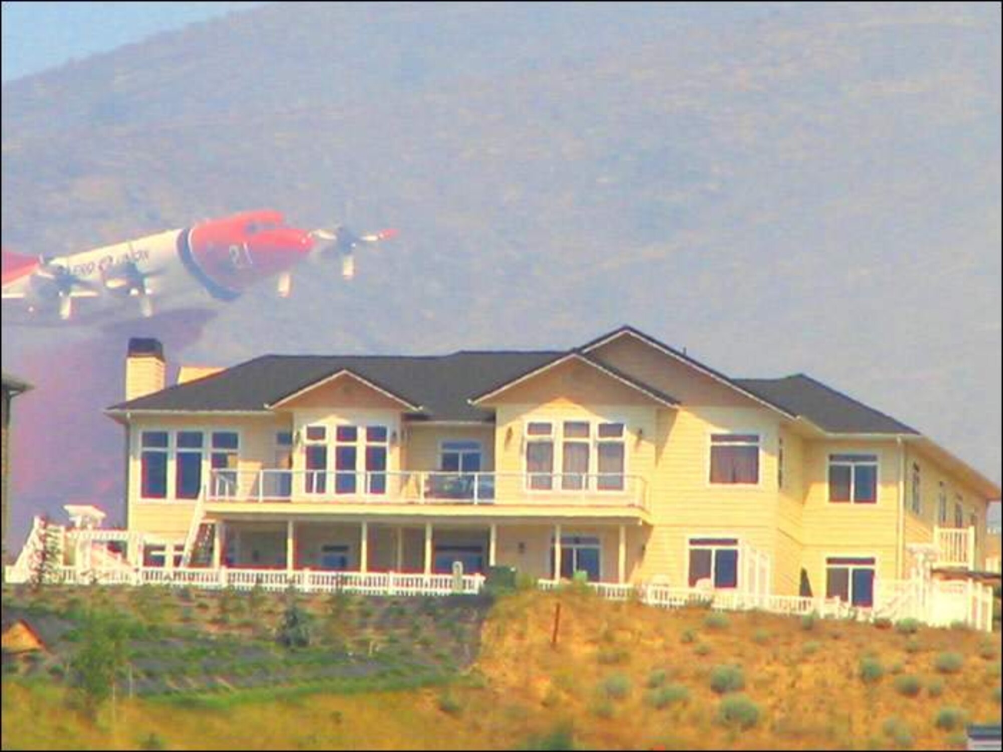 An Aero Union Corporation P-3 Orion drops red Phos-Chek fire retardant on a wildfire in an effort to save a building.  Aero Union aircraft fly out of the former McClellan Air Force Base in Sacramento, Calif.  (Photo courtesy of Aero Union)