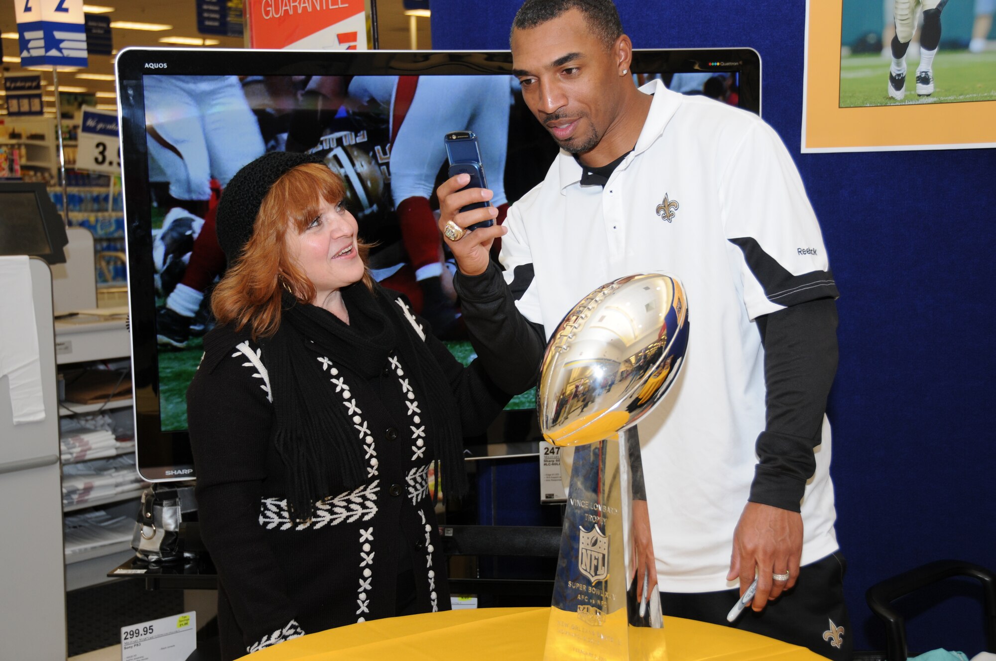 Left, Maria Arnold, spouse of retired Sailor Allen Arnorld,  and former New Orleans Saints' player, Michael Lewis used Maria's cell phone to take a photo of the two next to the Saints' Super Bowl trophy Feb. 4, 2011 at Keesler's Base Exchange