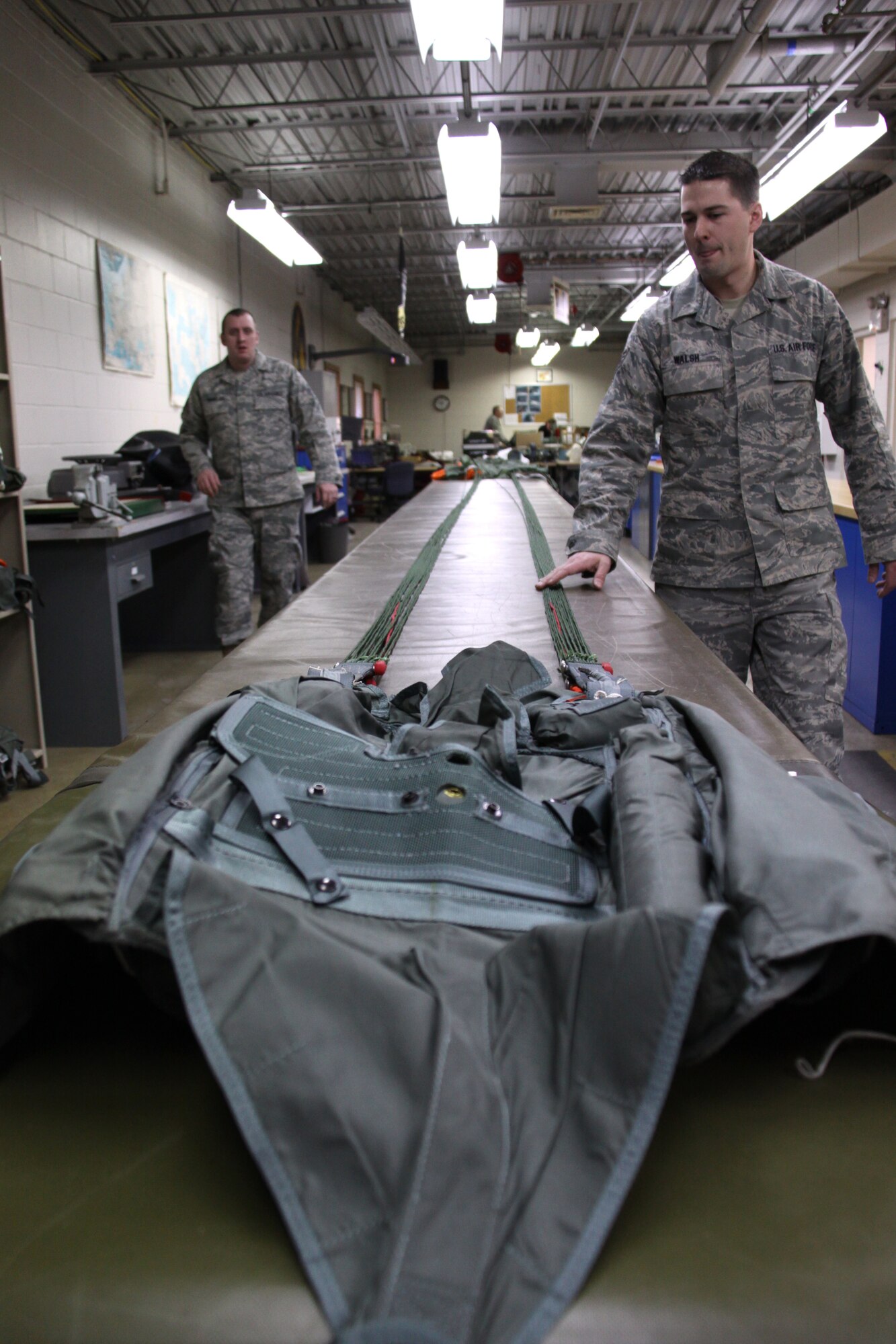 Staff Sgts.  Matt Walsh, an aircrew flight equipment specialist with the 911th Operations Support Squadron and Jason Cornelius, noncommissioned officer in charge of training, aircrew flight equipment, 911th OSS walk the length of a stretched-out BA-18 back parachute for inspection purposes here, Feb. 2. The parachutes are used on the C-130H cargo aircraft in the case of an emergency that would require aircrew to exit the plane during flight.