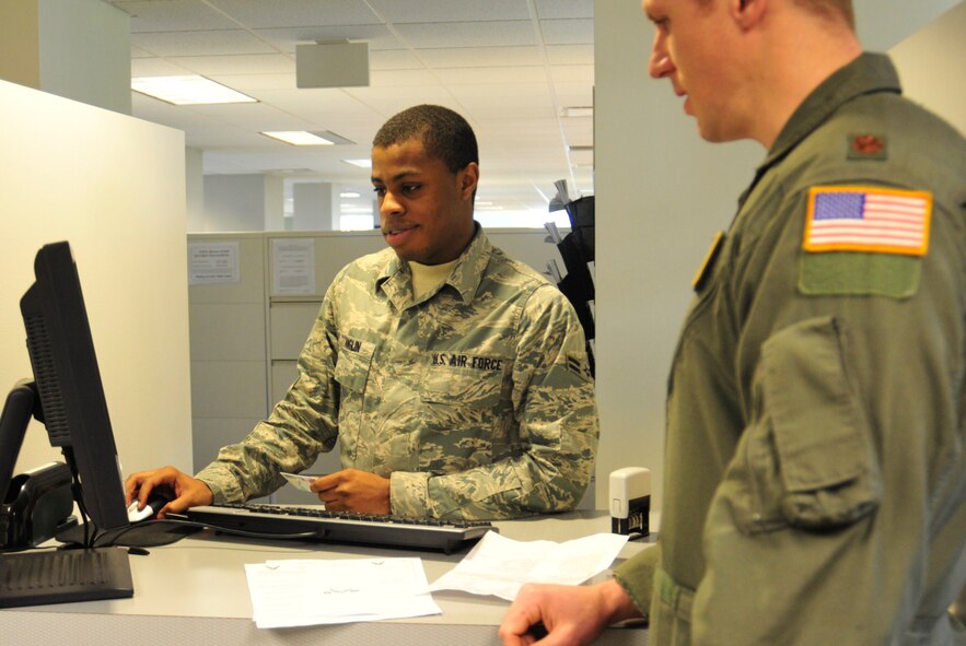 Airman 1st Class Frederick Anglin, left, 62nd Comptroller Squadron financial services technician, assists  Maj. Dustin Olson, 62nd Airlift Wing pilot, file a travel voucher for a recent mission supporting Operation Deep Freeze Feb. 2 at Joint Base Lewis-McChord, Wash. (U.S. Air Force photo/Airman 1st Class Leah Young)