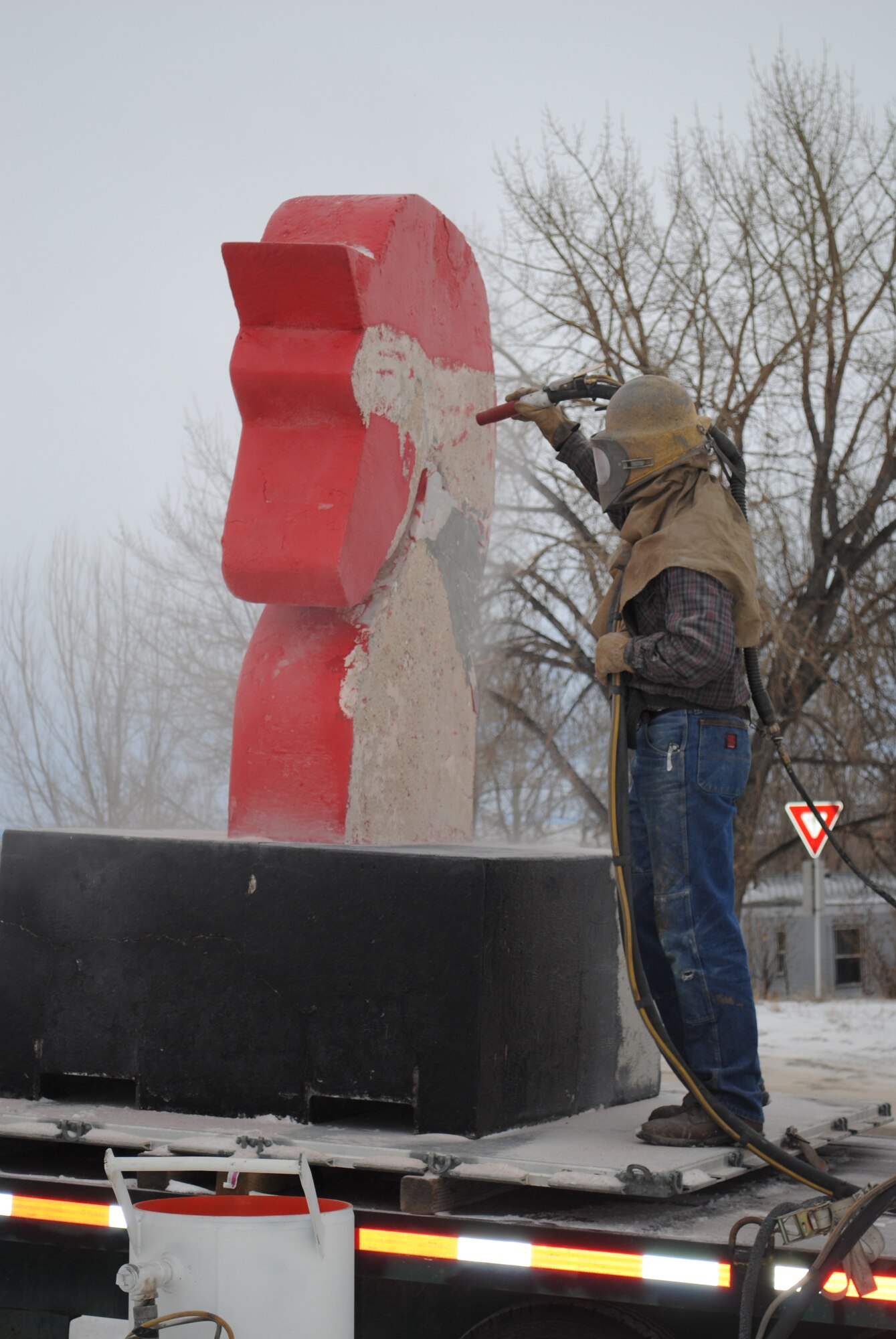 Mr. Phil Lane, a local business owner/operator sandblasts the paint off of the 819th RED HORSE Squadron statue.  Sandblasting the paint off was the first step in a two-day restoration process.  (U.S. Air Force photo/Airman Cortney Hansen)