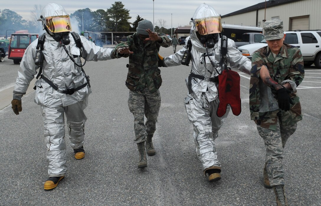 LANGLEY AIR FORCE BASE, Va. -- Staff Sgt. Joseph Dunn and Senior Airman Ryan Gross, 633d Civil Engineer Squadron Fire Department firefighters, escort Airmen with mock burns away from the scene of a simulated explosion during a Major Accident Response Exercise Feb. 4. MAREs are held on a semi-annual basis to certify and train base emergency responders. (U.S. Air Force photo / Senior Airman Wesley Farnsworth) (RELEASED)