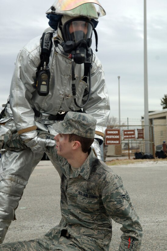 LANGLEY AIR FORCE BASE, Va. -- Staff Sgt. Joseph Dunn, 633d Civil Engineer Squadron Fire Department firefighter, assists Airman 1st Class Seth Dillinger, 633d Medical Group Pharmacy technician, during a Toxic Industrial Chemical/Toxic Industrial Material simulation here, Feb. 4. The Major Accident Response Exercise was held as a required semi-annual evaluation to examine first respnders' ability to quickly react and stabilize real-world emergencies. (U.S. Air Force photo/Airman 1st Class Racheal Watson)(RELEASED)