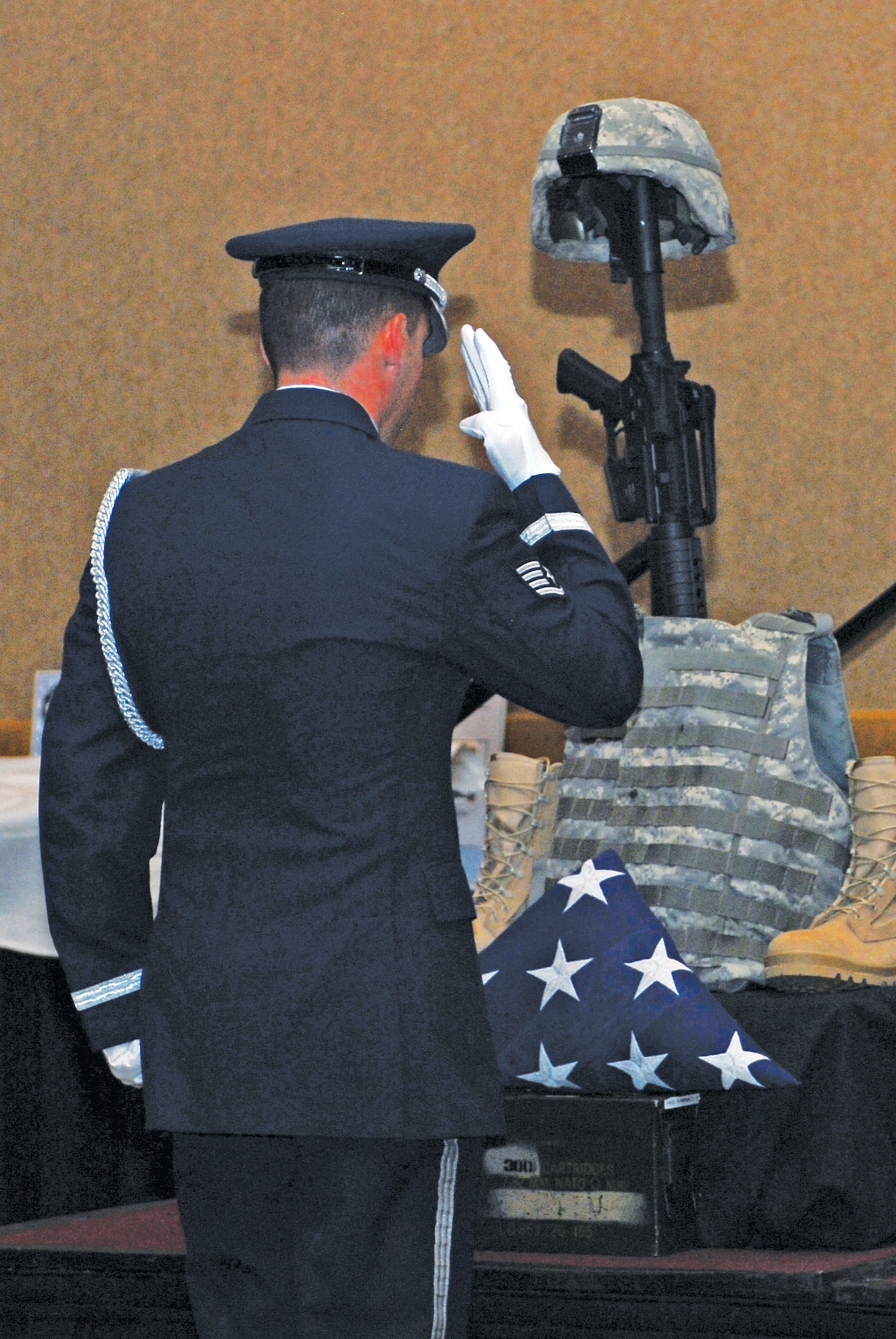 Staff Sgt. Mark Crotsley, Luke Air Force Base Honor Guard, salutes the folded flag placed at the foot of the Battlefield Cross durign the 2010 Annual Awards Banquet on Jan. 29th held at the Wigwam Spa and Resort in Litchfield Park, Ariz.  The cross is erected to show respect to fallen Airman on the battlefield.  (U.S. Air Force photo/Senior Airman Tracie Forte)