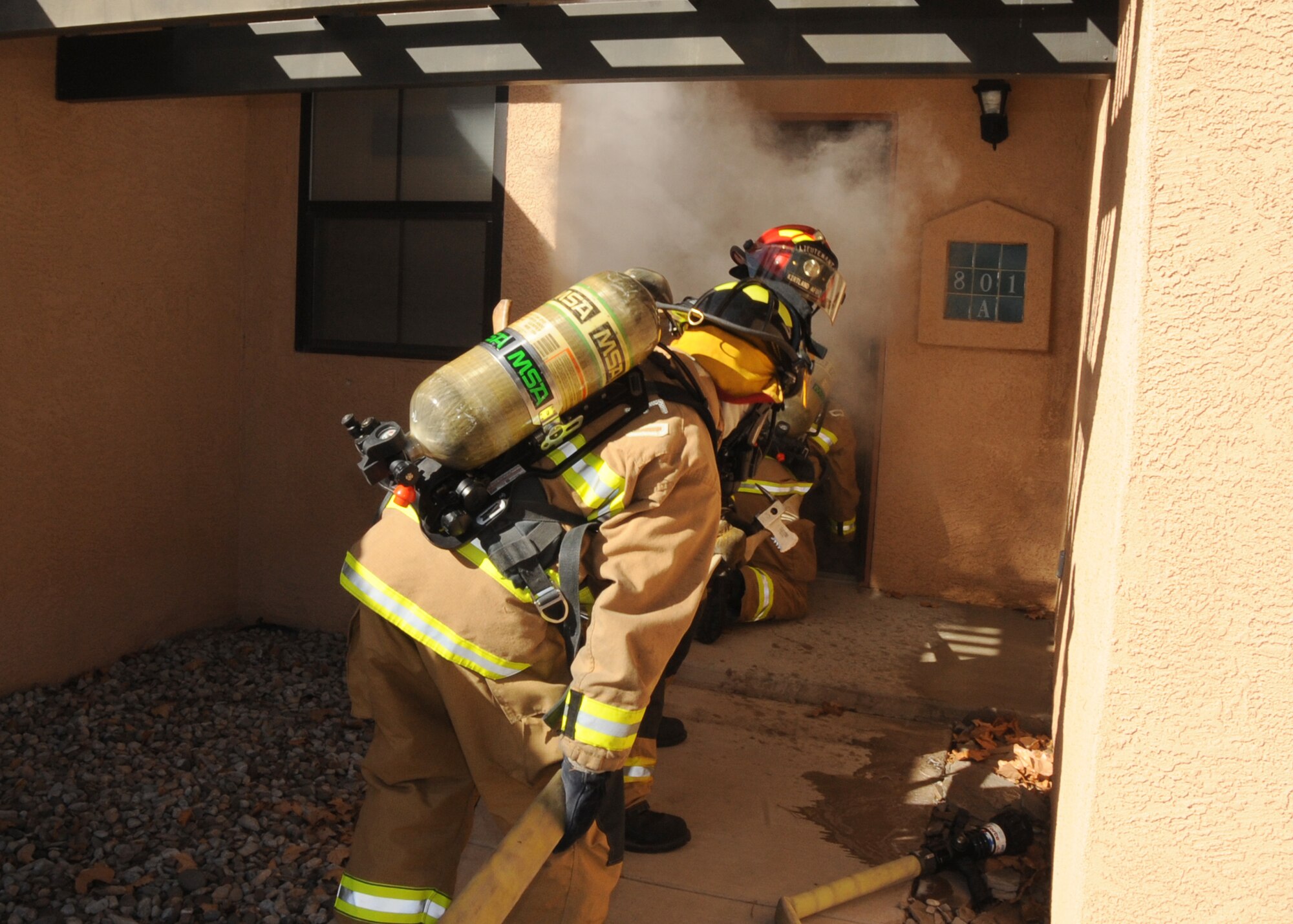 Firemen prepare to enter a burning house.  U.S. Air Force Photo by Dennis Carlson.