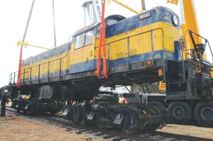 Evans, (left), watches as the cranes begin lowering the engine onto its trucks.

