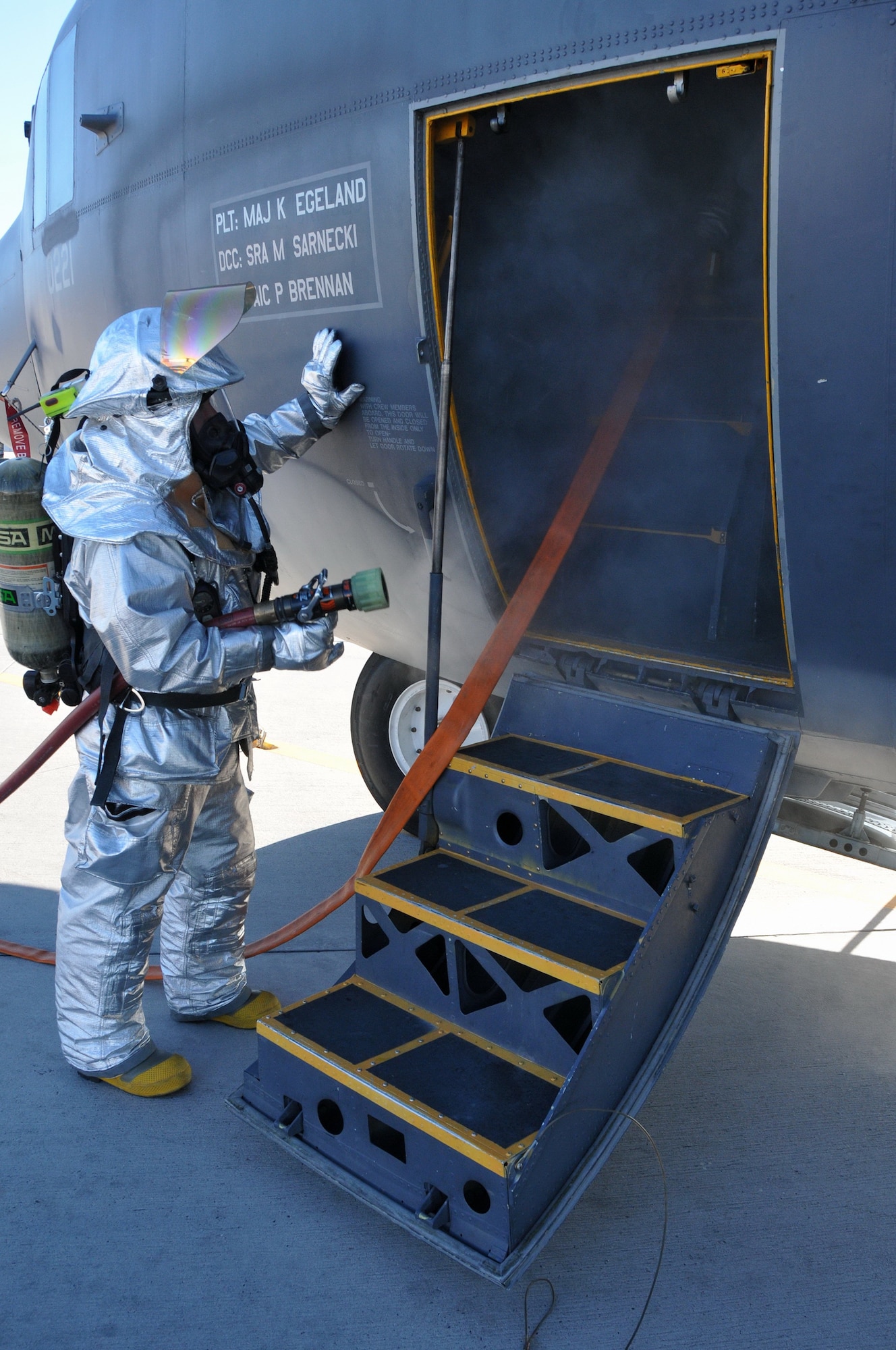 A fireman simulates dousing a fake fire on board a C-130.  U.S. Air Force Photo by Ken Moore.