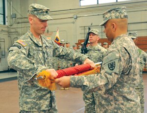 Lt. Col. Steven Wilke (left), and Command Sgt. Maj. John Harris (right), Special Troops Battalion command team, roll the battalion colors for casing. The STB will deploy to Afghanistan next month in support of overseas contingency operations.

