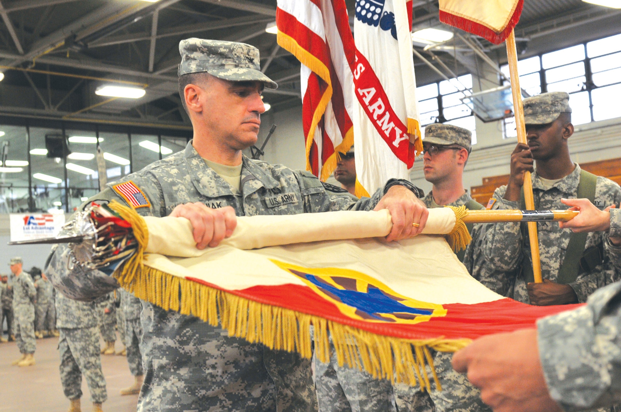 Col. Lawrence Kominiak, commander, 7th Sustainment Brigade, rolls the brigade colors for casing during a deployment ceremony Jan. 28 at Fort Eustis’ Anderson Field House. The brigade’s Headquarters and Headquarters Company, Special Troops Battalion is deploying about 300 Soldiers to Afghanistan later this month where they will provide command and control of operational combat service support and Title Ten oversight for logistics operations to all U.S. forces and other identified international security assistance forces.