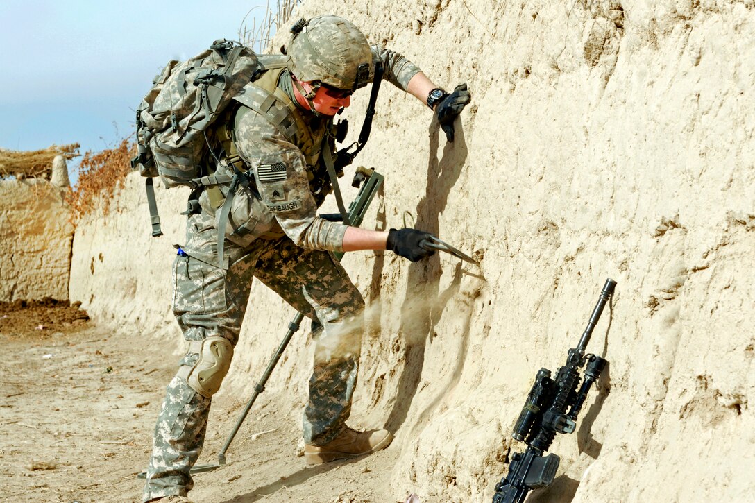 U.S. Army Sgt. Jonathian Defibaugh uses his tactical hatchet to carve foot holes into a wall in the Arghandab district in Afghanistan's Kandahar province, Jan. 31, 2011.