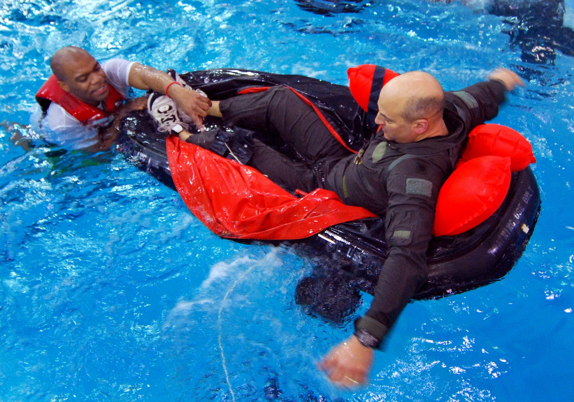 Tech Sgt. Preston Caldwell, an Aircrew Flight Equipment Continuation Instructor, assists C-130 pilot, Lt. Col. David Re with utilizing an aircrew survival raft during the semiannual water survival training for 94th Airlift Wing aircrew members, 4 Feb.  Aircrew personnel are required to receive this training once every three years to stay proficient with the equipment and techniques used in a water survival situation.  The Aircrew Flight Equipment Continuation instructors conduct this training twice a year and have partnered with Cobb County to use the Cobb Aquatic Center in Marietta, Ga., for each winter session to ensure a safe training environment.  (U.S. Air Force photo/ Brad Fallin)
