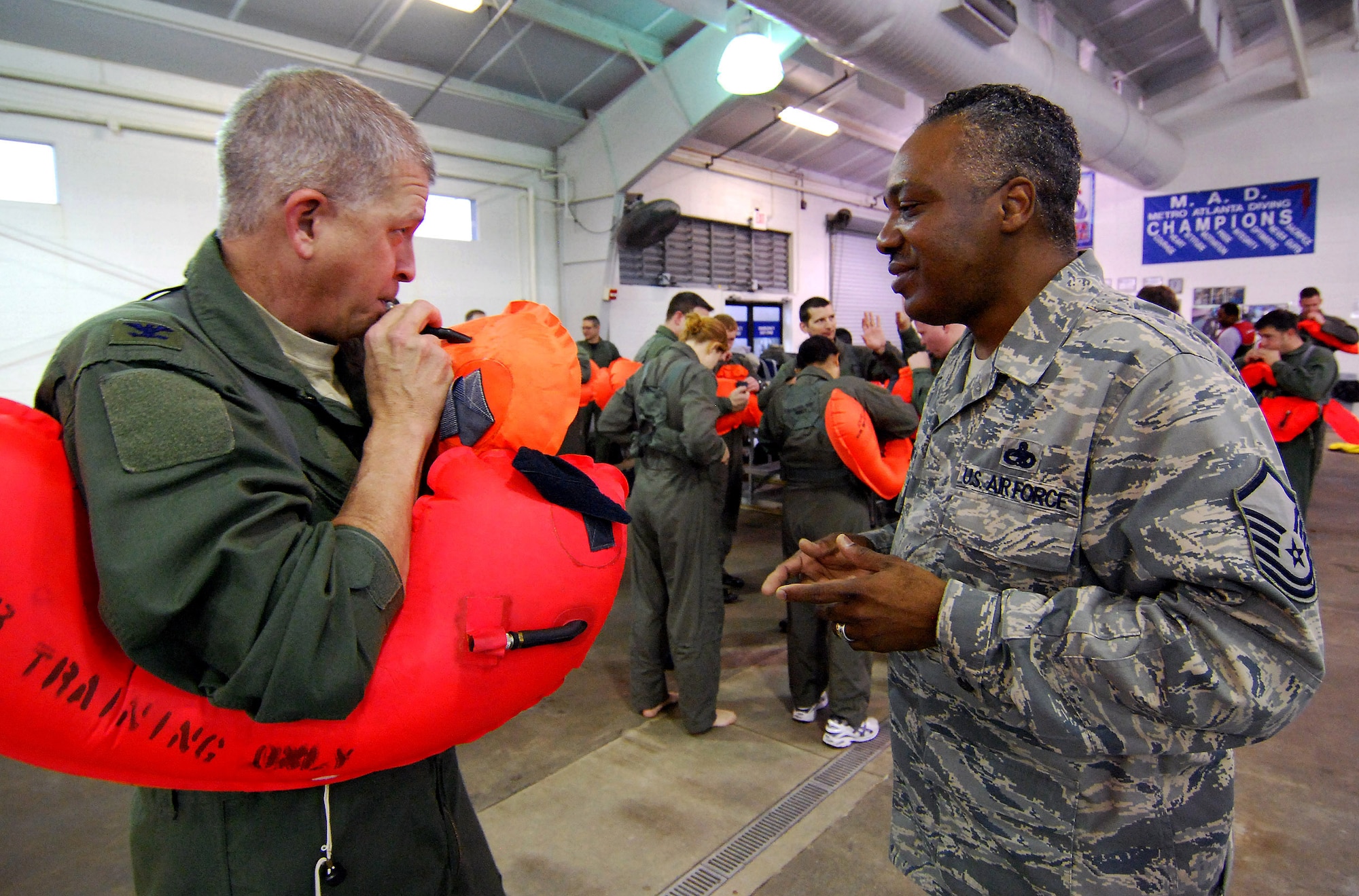 Col. Timothy Tarchick, 94th Airlift Wing commander, inflates the personal life preserver used in the aircrew water survival class as Aircrew Flight Equipment Training NCOIC, Master Sgt. Mike Varnado monitors his progress, 4 Feb.  Aircrew members are required to receive this training once every three years to stay proficient with the equipment and techniques used in a water survival situation.  The Aircrew Flight Equipment Continuation instructors conduct this training twice a year and have partnered with Cobb County to use the Cobb Aquatic Center in Marietta, Ga., for each winter session to ensure a safe training environment.  (U.S. Air Force photo/ Brad Fallin)