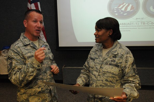 Senior Master Sgt. Chris Amburn presents a newly designed Chapter 7 challenge coin to Chief Master Sgt. Deborah F. Davidson.  Davidson, Paul H. Lankford Enlisted Professional Military Education Center Commandant spoke to the November gathering of the NCO Academy Graduates Association Chapter 7 in Charlotte. Photo by Tech. Sgt. Richard Kerner.