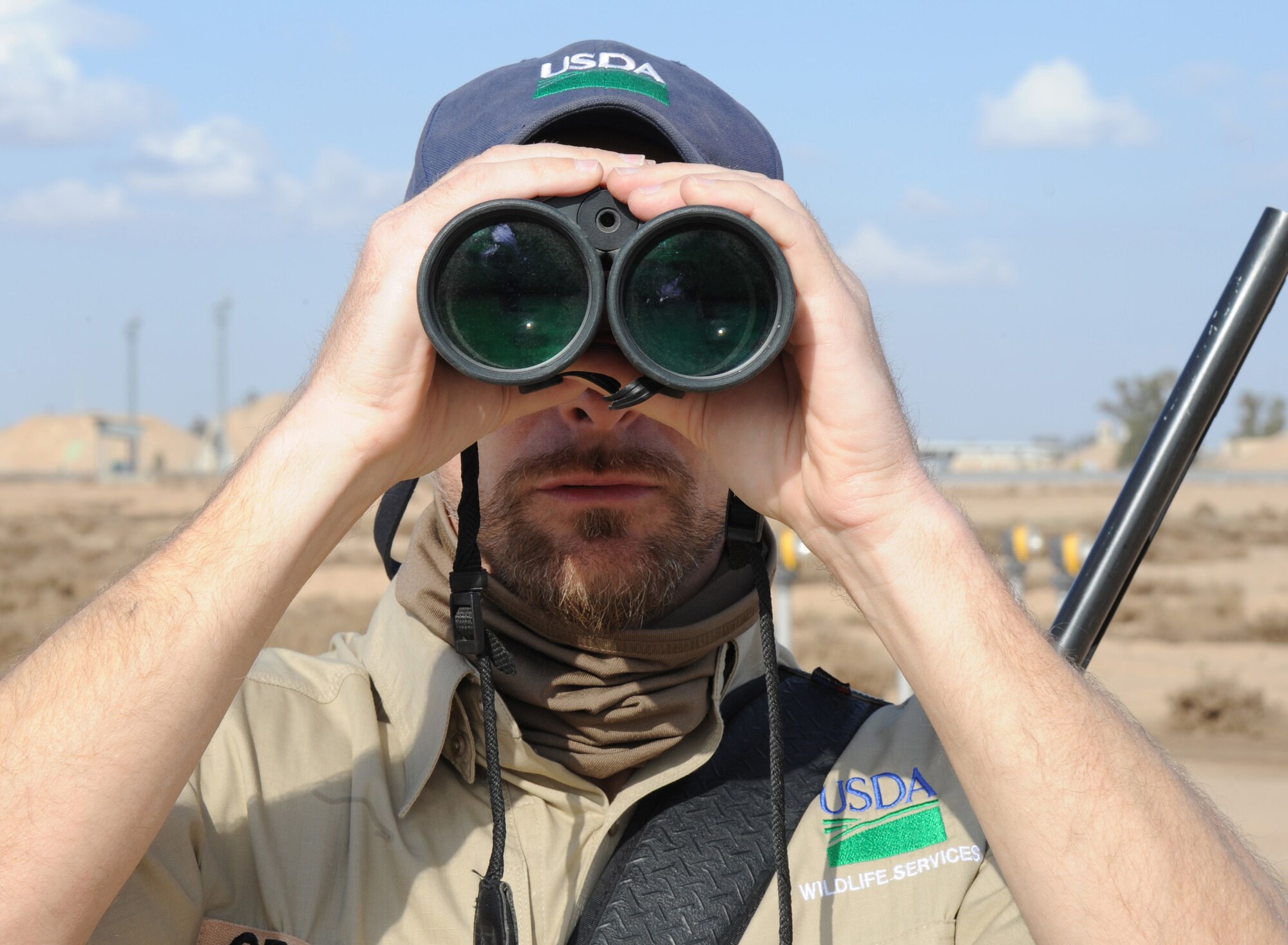JOINT BASE BALAD, Iraq-- Mr. John Griffin, U.S. Department of Agriculture wildlife biologist with the 332nd Air Expeditionary Wing flight safety office, scans the airfield for wildlife Jan. 31, 2011. Flight safety is responsible for reducing the risk of aircraft strike threats by managing and identifying hazards on and off base. Mr. Griffin works for USDA Wildlife Services and is deployed from Moody Air Force Base, Ga. (U.S. Air Force photo/ Staff Sgt. Keyonna Fennell)