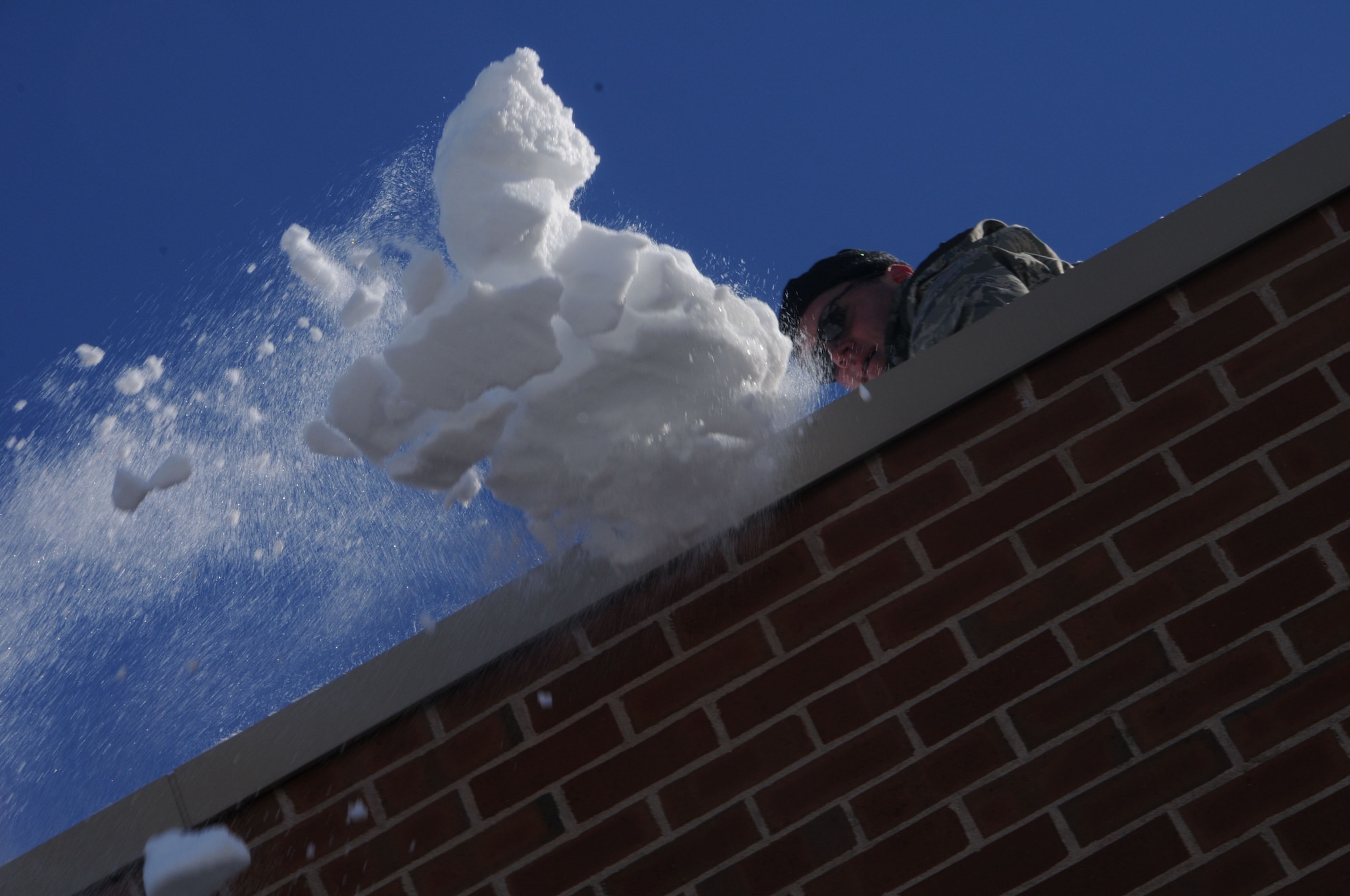 Lt. Col. Kevin McManaman, commander, 118th Airlift Squadron, throws a shovelful of snow from the roof of Tolland High School Jan. 4, 2011, after the town's schools were closed over safety concerns and town officials requested help from the Connecticut National Guard. Approximately 125 Guardsmen were activated and worked from sunrise to sunset there and at the town’s middle school. Heavy snow this winter has recently caused several roof collapses across the state. (U.S. Air Force photo by Tech. Sgt. Tedd Andrews) 