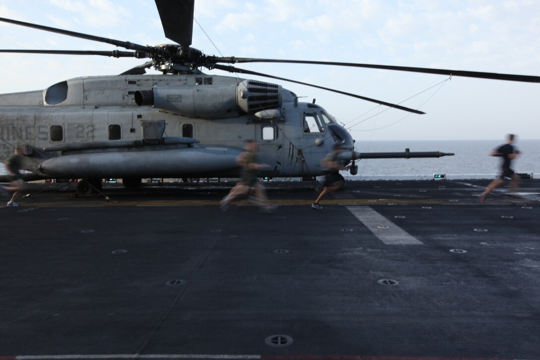 USS KEARSARGE, At Sea (Feb. 7, 2011) – Runners dash by a CH-53 Super Stallion during the Run To Nowhere, a 5K race held Feb. 7, 2011. Marines and sailors with 26th MEU and USS Kearsarge participated in the run, which spanned from the bow to the stern of the ship as well as the cavernous hangar bay. Elements of 26th MEU are currently operating aboard ships of the Kearsarge Amphibious Ready Group in the U.S. 5th Fleet area of responsibility. (Official USMC photo by Lance Cpl. Michael S. Lockett)