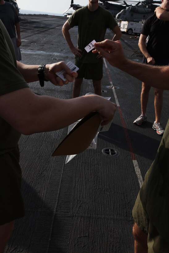 USS KEARSARGE, At Sea (Feb. 7, 2011) – One of the participants chooses the next winner by drawing a number out of the bag during the lottery after the Run To Nowhere, a 5K race held Feb. 7, 2011. Marines and sailors with 26th Marine Expeditionary Unit and USS Kearsarge participated in the run, which spanned from the bow to the stern of the ship as well as the cavernous hangar bay. Elements of 26th MEU are currently operating aboard ships of the Kearsarge Amphibious Ready Group in the U.S. 5th Fleet area of responsibility. (Official USMC photo by Lance Cpl. Michael S. Lockett)::r::::n::