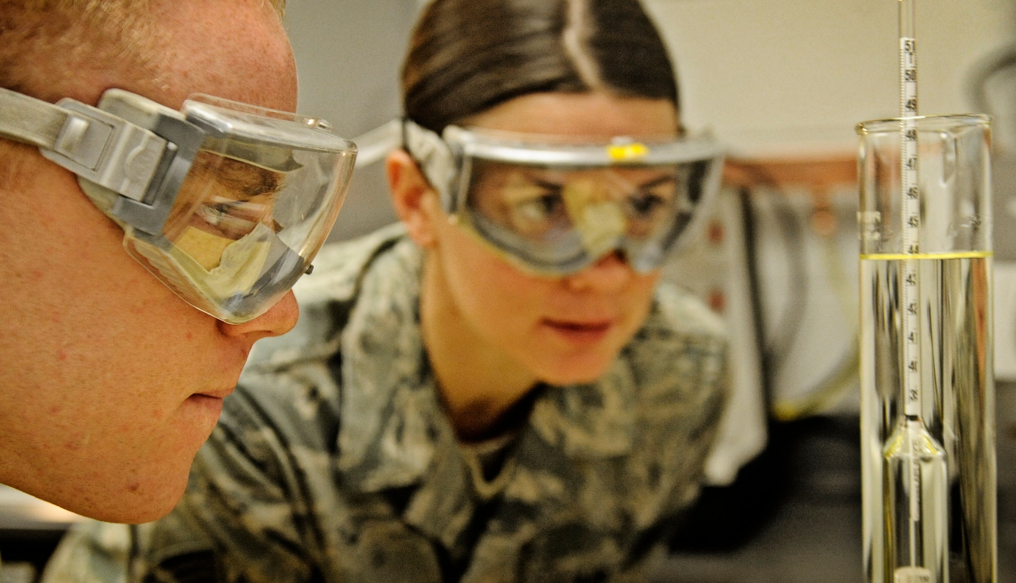 Airman 1st Class Lucas Sinnott, 375th Logistics Readiness Squadron fuels lab technician, and Tech Sgt. Kelly Gahn, fuels laboratory NCO in charge, observe a cylinder of JP-8 fuel during a weight test Feb 4, 2011 at Scott Air Force Base. The petroleum, oils and lubricants flight laboratory is responsible for testing fuel quality along with other aspects of the fuel. (U.S. Air Force photo/ Staff Sgt. Ryan Crane)