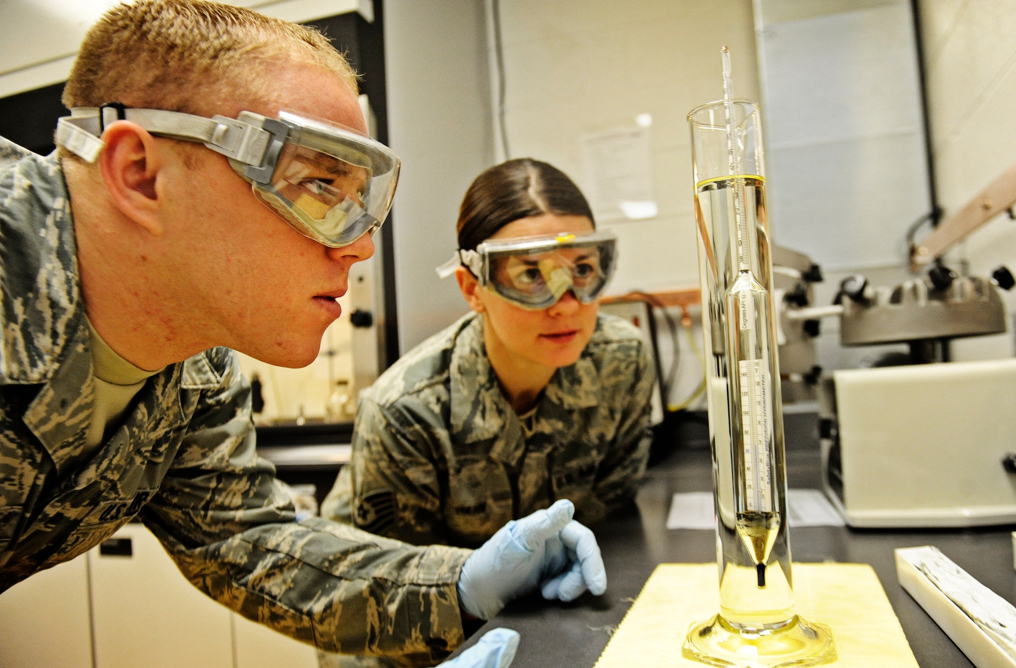 Airman 1st Class Lucas Sinnott, 375th Logistics Readiness Squadron fuels lab technician, and Tech Sgt. Kelly Gahn, fuels laboratory NCO in charge, observe a cylinder of JP-8 fuel during a weight test Feb 4, 2011 at Scott Air Force Base. The petroleum, oils and lubricants flight laboratory is responsible for testing fuel quality along with other aspects of the fuel. (U.S. Air Force photo/ Staff Sgt. Ryan Crane)