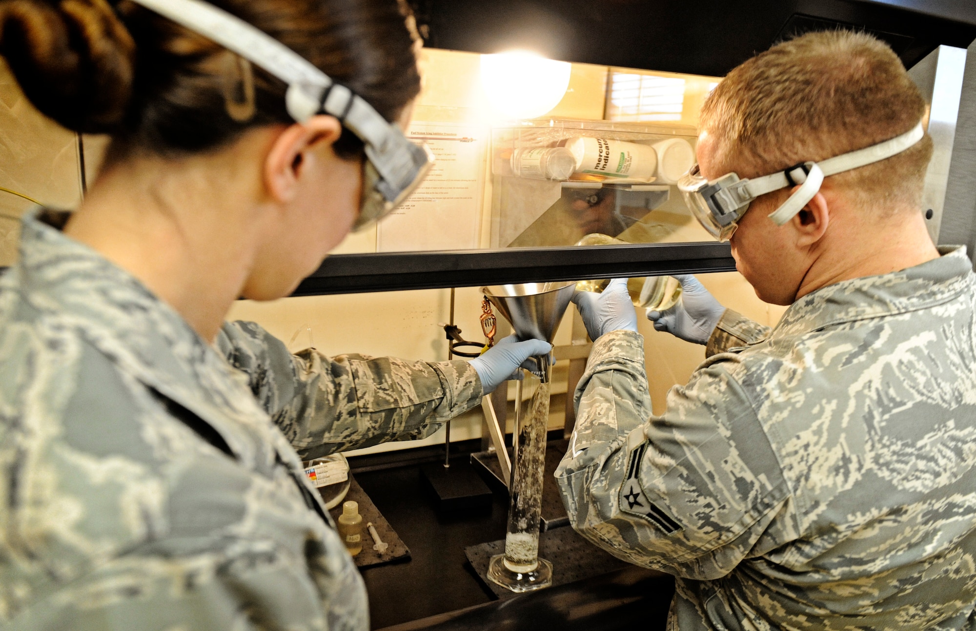 Tech Sgt. Kelly Gahn, 375th Logistics Readiness Squadron fuels laboratory NCO in charge, assists Airman 1st Class Lucas Sinnott, fuels lab technician, with the measurement of JP-8 fuel during a weight test Feb 4, 2011 at Scott Air Force Base. The petroleum, oils and lubricants flight laboratory is responsible for testing fuel quality along with other aspects of the fuel. (U.S. Air Force photo/ Staff Sgt. Ryan Crane)