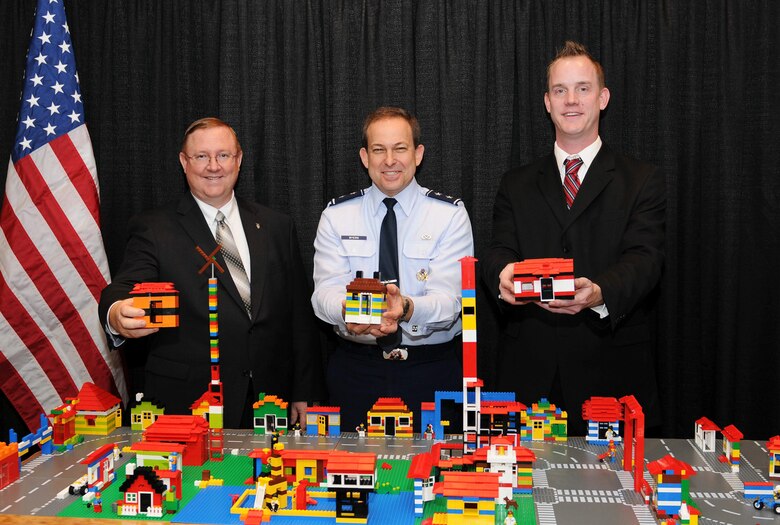 Terry Edwards (left), Maj. Gen. Timothy A. Byers (center) and Troy Peloquin show off some of the miniature houses built out of toy building blocks by attendees at the Professional Housing Management Association Professional Development Seminar in New Orleans. The building blocks, which were available at the Air Force's Housing trade-show booth to promote teamwork and customer service as building blocks for communities, were donated to the local school district to be enjoyed by local students. Mr. Edwards is the director of the Air Force Center for Engineering and Environment. General Byers is the Air Force civil engineer. Mr. Peloquin is the donations coordinator for the Louisiana Recovery School District.