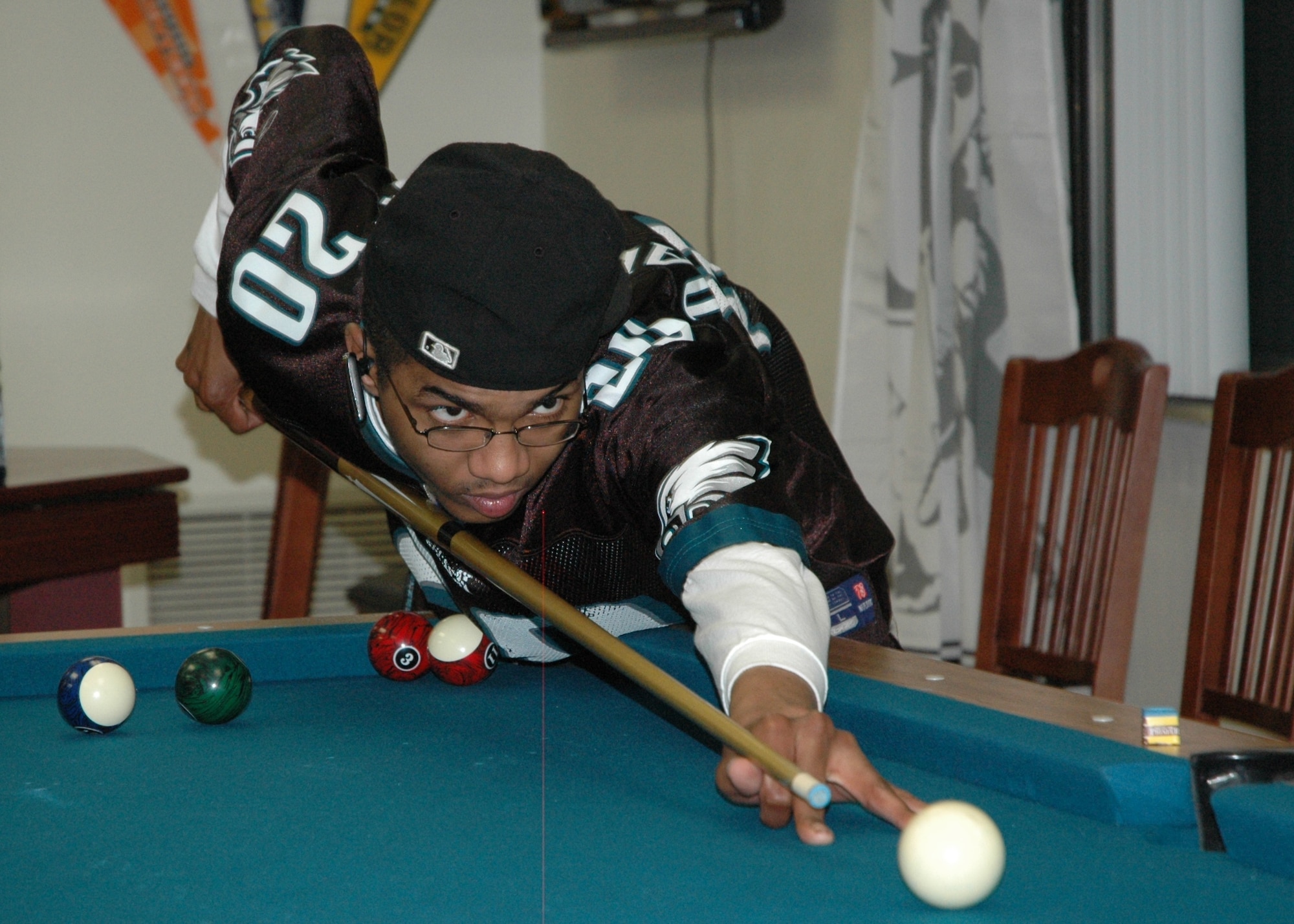 Airman 1st Class Eric Lewis, 96th Medical Support Squadron laboratory technician, cues up a game of pool while watching the NFL Super Bowl Feb. 6. The football match drew 37 dorm residents to Eglin's new Airmen Center called "Lighthouse" located in Dorm 18 D's third floor. Entrance for the facility is accessible from the Airmen Leadership School's parking lot. (U.S. Air Force photo/Chrissy Cuttita)