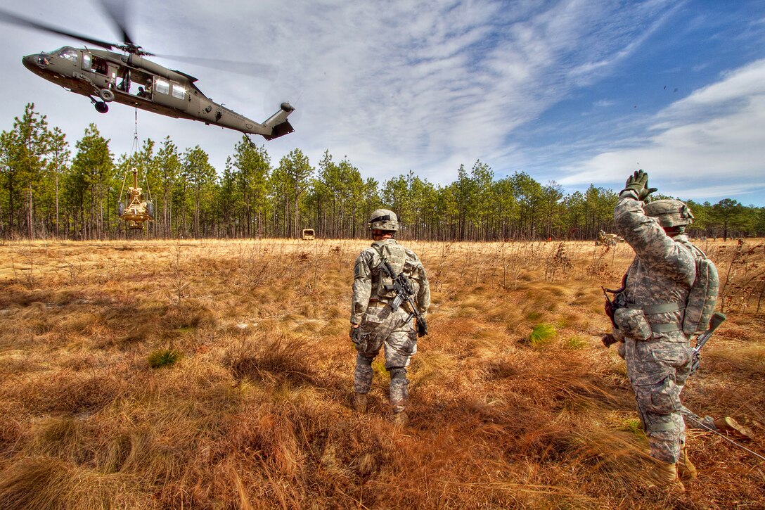 U.S. Army 1st Sgt. Federico Despiau, right, signals to a UH-60M Black Hawk helicopter that it is clear to take off during air assault training on Fort Bragg, N.C., Feb. 2, 2011.