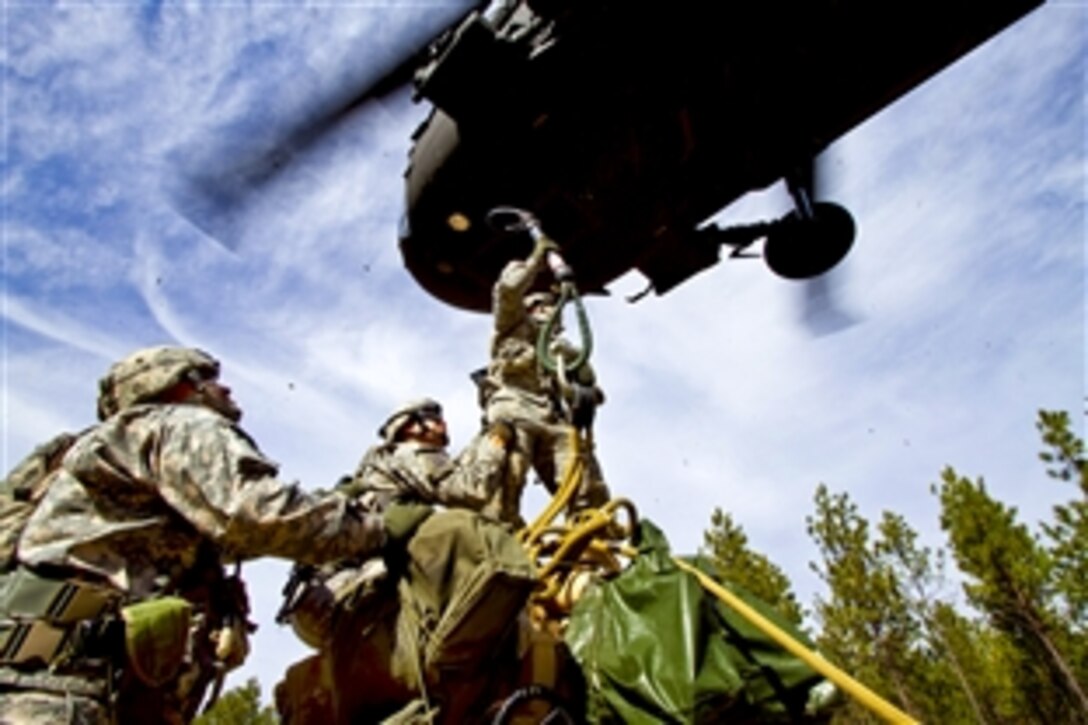 U.S. Army Spc. Josh Estrello attempts to hook an M119A2 105mm howitzer to an approaching UH-60M Black Hawk helicopter with assistance from 1st Sgt. Federico Despiau and Staff Sgt. Robert Novak during an air assault training mission on Fort Bragg, N.C., Feb. 2, 2011. Estrello, Despiau and Novak are assigned to the 82nd Airborne Divison’s 1st Brigade Combat Team.